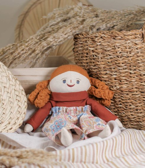 Blue-eyed Little Lenni doll Anna, sitting dressed in a floral high waist trousers and terracotta turtleneck. Organic, natural materials. Handmade doll.