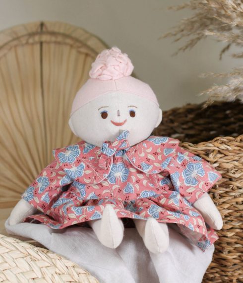 Little Lenni lutka Ema, sa ružičastom punđom, sjedi u cvjetnoj haljinici – ručna izrada, organski materijali.